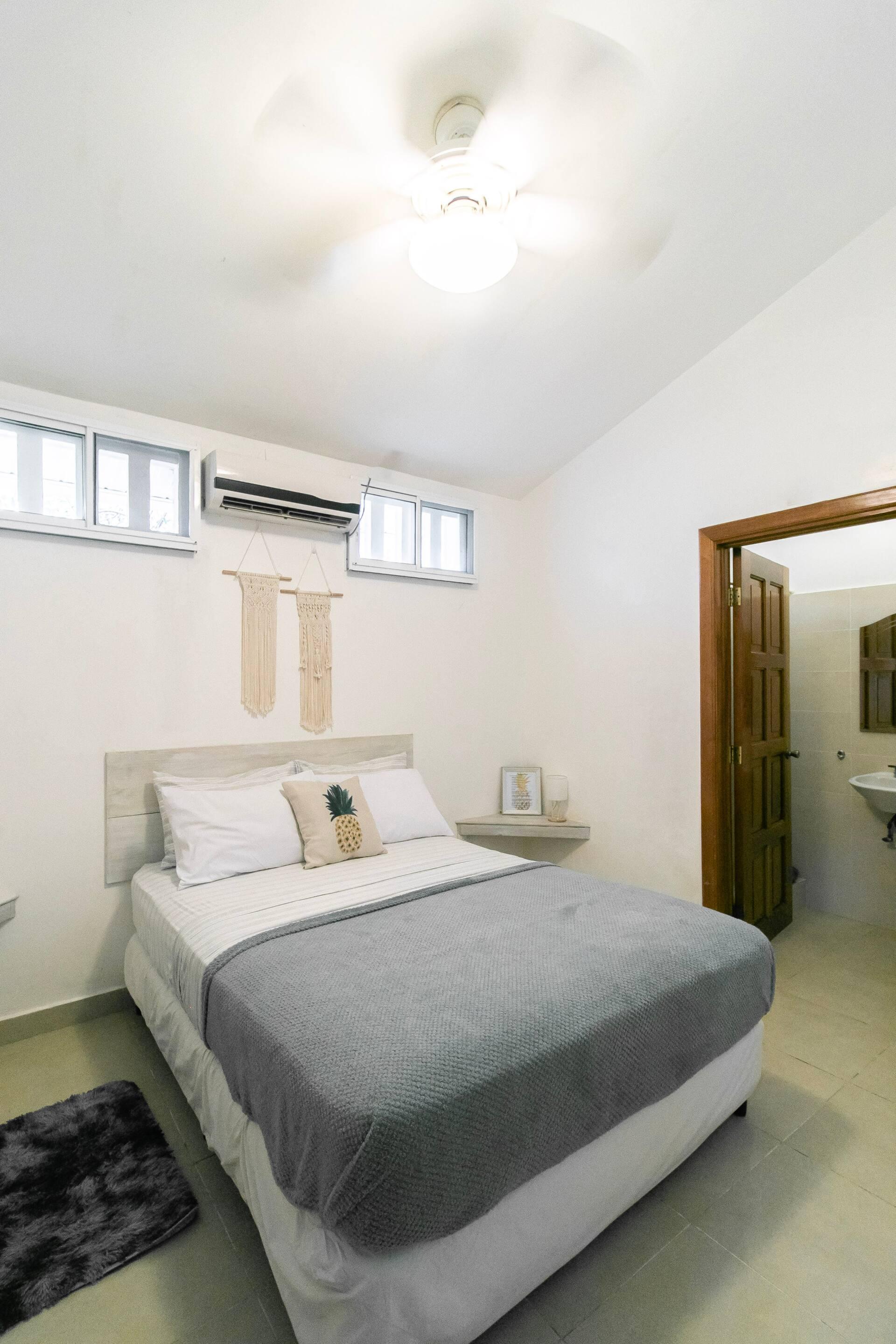 A guest room with queen bed, air conditioning and the en suite door