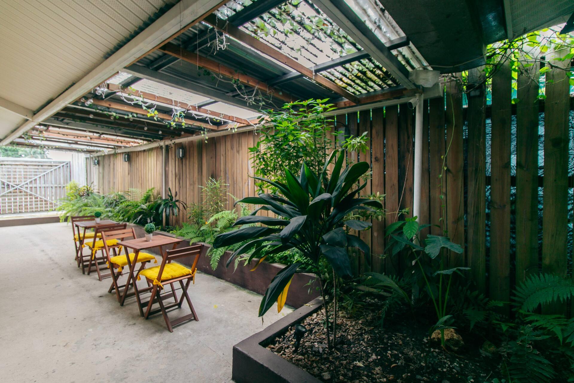 Timber tables and yellow chairs beside the planted courtyard